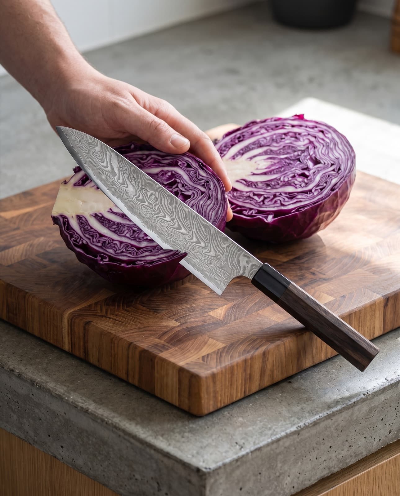 Le gyuto vient de couper un chou rouge en deux sur une planche en bois, la coupe violette et blanche bien visible